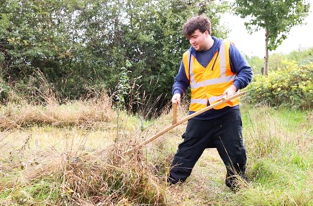 Participants supported in scything one of the natural meadows in Hounslow Heath