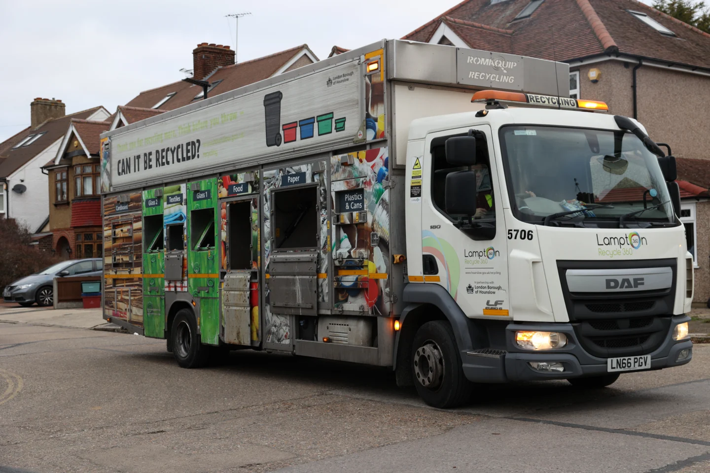 A recycling van, parked on a street.